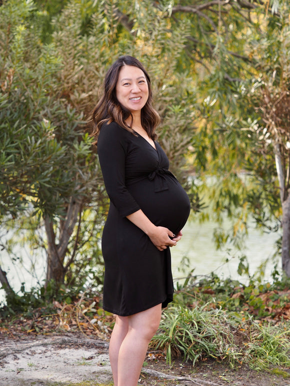 Pregnant woman wearing a black maternity wrap dress.