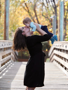 Pregnant woman wearing a black maternity wrap dress.